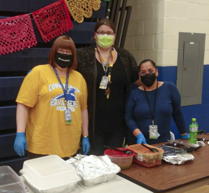 Ladies posing for a picture behind food table