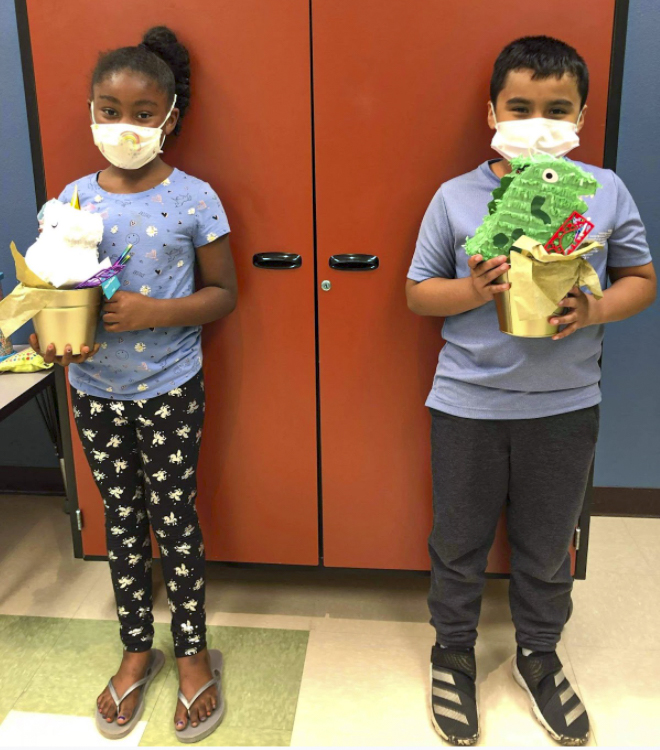 Students holding small piñatas
