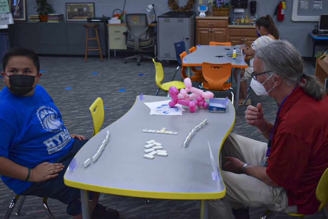 Student and adult playing dominos