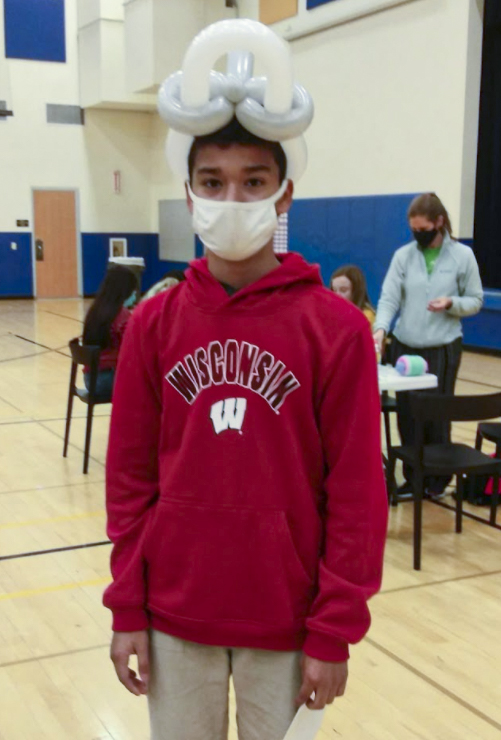 Student standing with a balloon hat